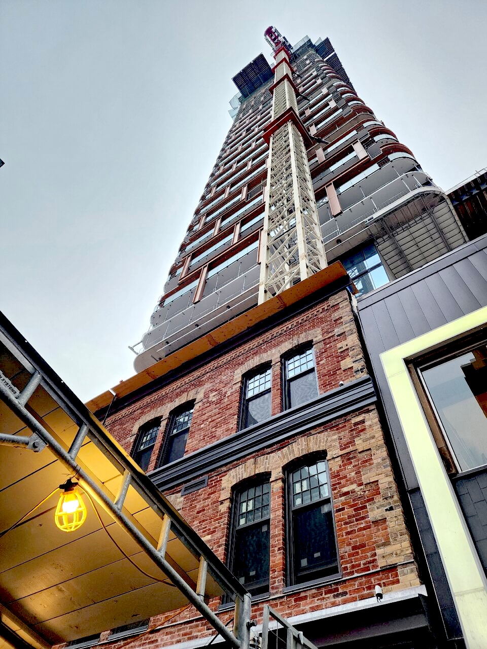 Victorian divided-light windows with a crane behind them at 8 Elm in Toronto