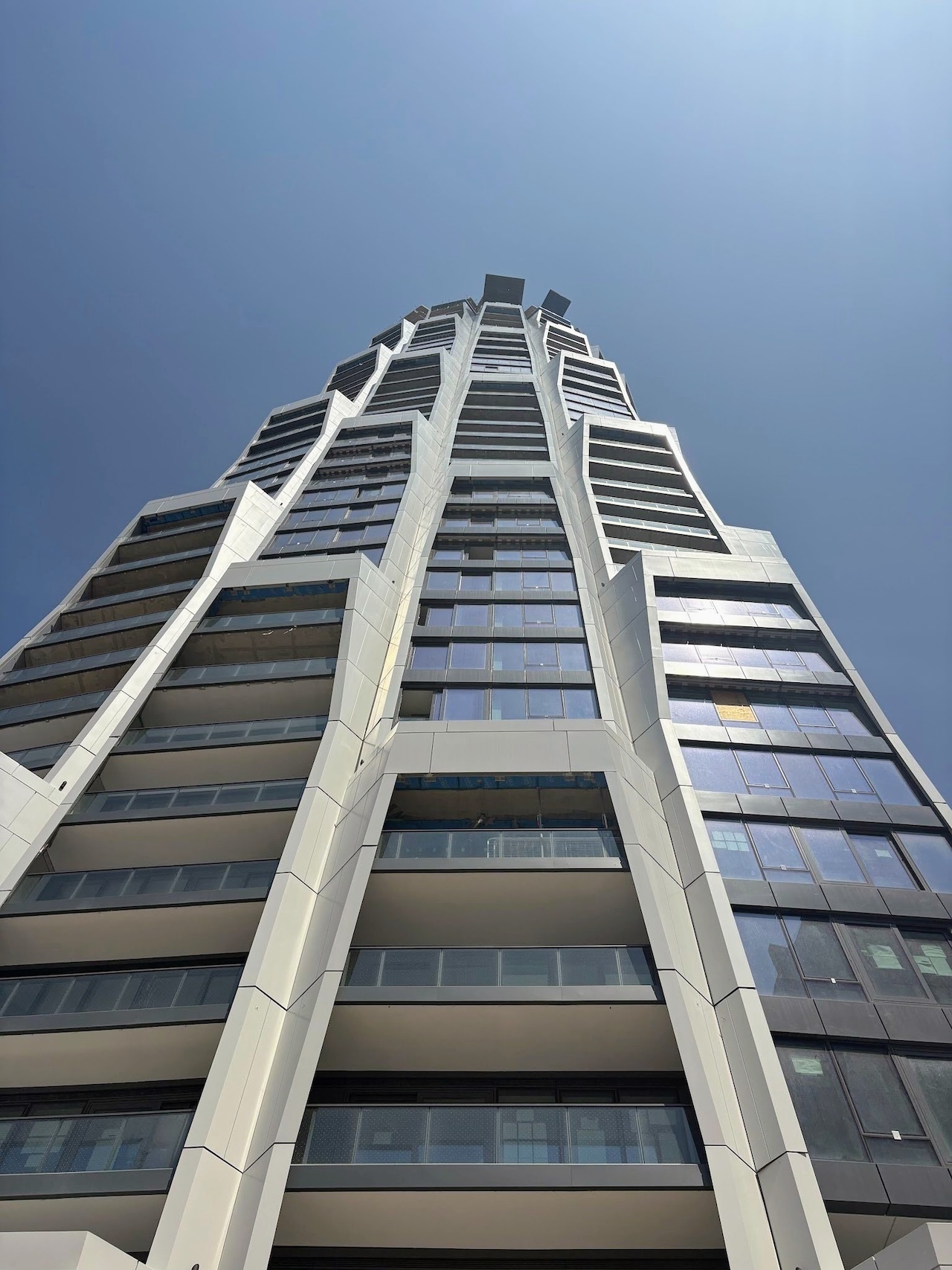 Looking up at One Delisle showing rotating modules, stepped floor plates, and private terraces